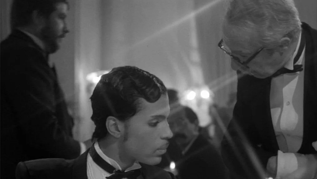 Under The Cherry Moon (1986) movie still: medium — An elegant evening event features guests seated at tables under warm, soft light. Prince in a…