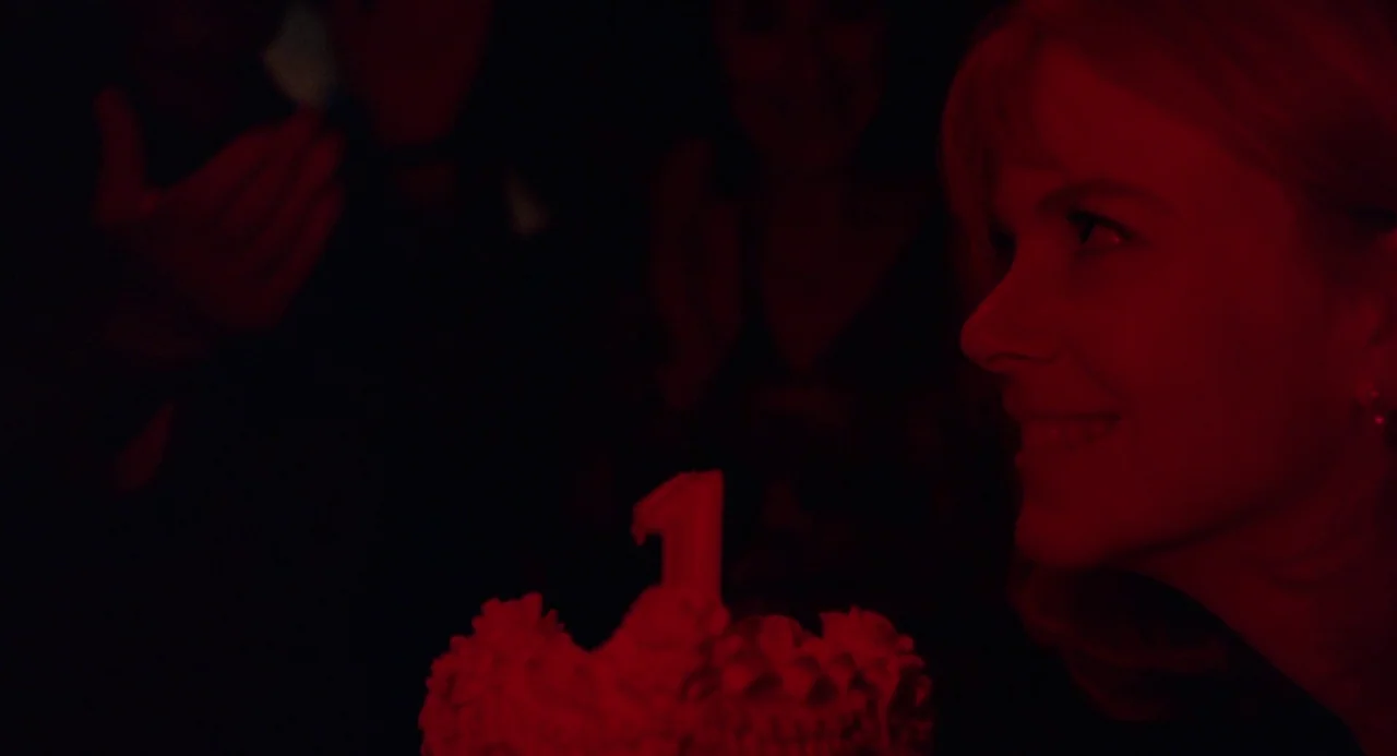 To Die For (1995) movie still: closeup — A woman stares at a lit candle on a cake in a darkened room. She is illuminated only by the red glow of the…
