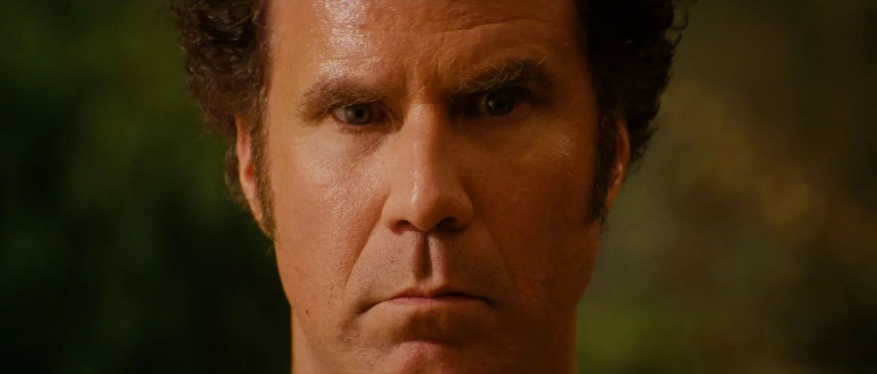 Casa De Mi Padre (2012) movie still: closeup — An outdoor night setting featuring dark blurred foliage in the background. A man stares directly into…