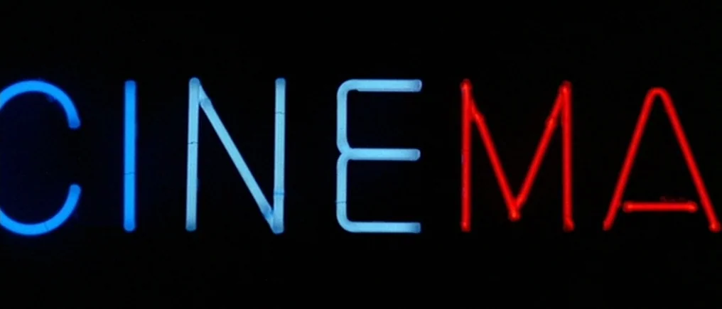 Pierrot Le Fou (Crazy Pete) (1965) movie still: closeup — A glowing neon sign spells out the word CINEMA in blue and red tubes. The letters are…