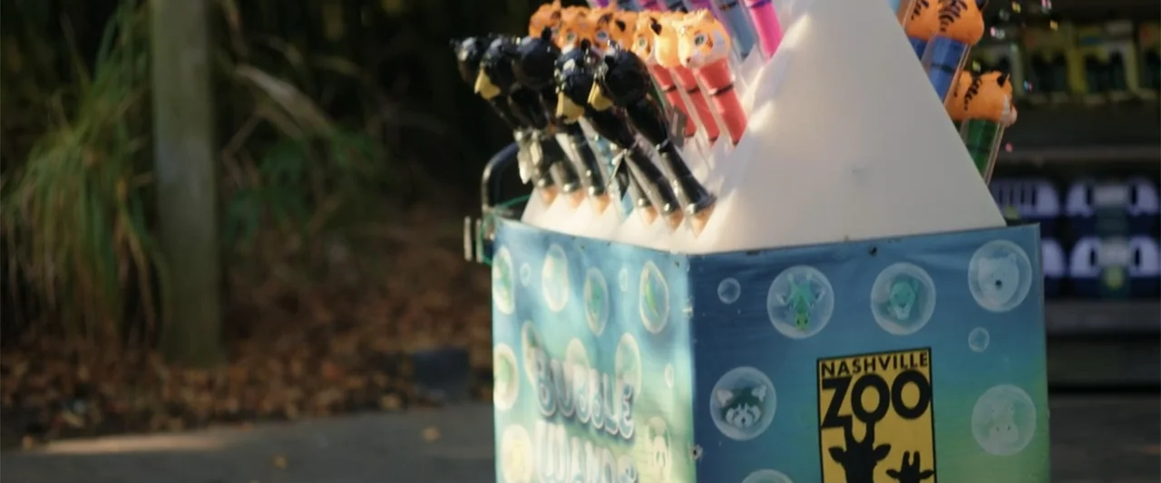 Someone Like You (2024) movie still: medium — A portable display box for bubble wands sits outdoors on a paved walkway. The box features Nashville…