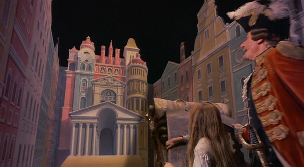 The Adventures Of Baron Munchausen (1988) movie still: medium — A theatrical stage set consists of painted two-dimensional buildings and a classical…