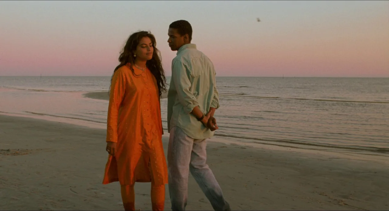 Mississippi Masala (1991) movie still: fullbody — A flat sandy beach at golden hour stretches toward the calm, flat ocean horizon. A man and a woman…