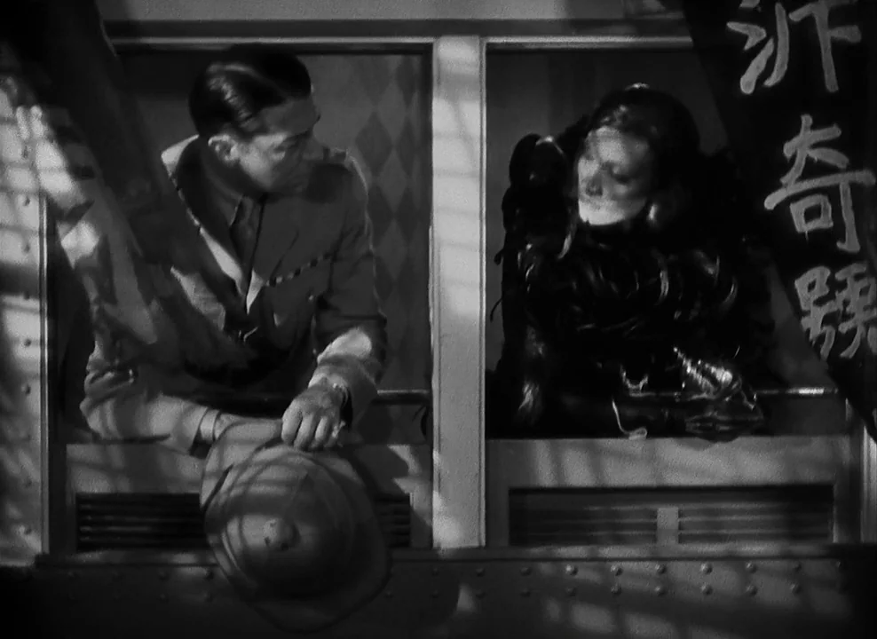 Shanghai Express (1932) movie still: medium — A dark train compartment features two adjacent open windows with slatted shades. A uniformed man holds…