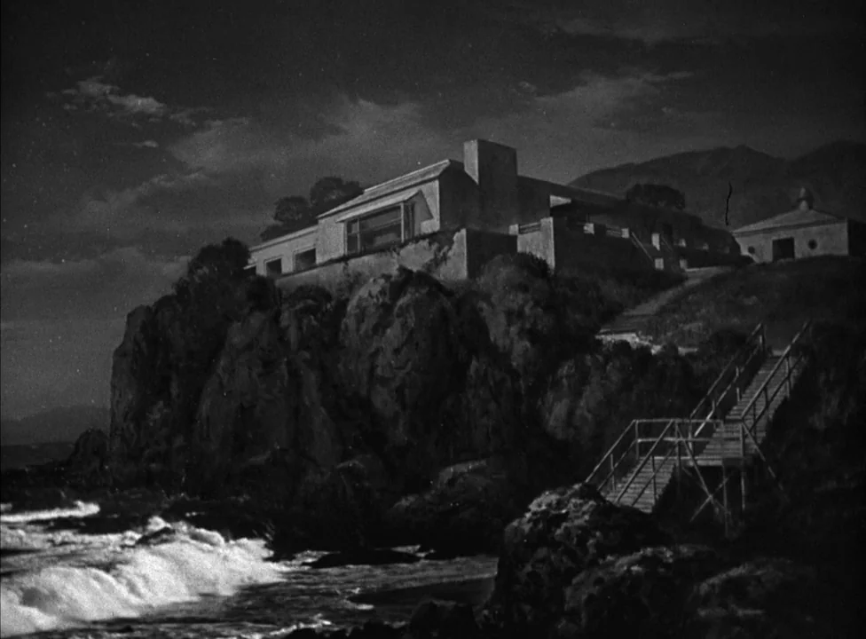 Murder, My Sweet (1944) movie still: establishing — A modern residence sits atop a steep, jagged cliff overlooking a dark ocean. Wooden stairs…
