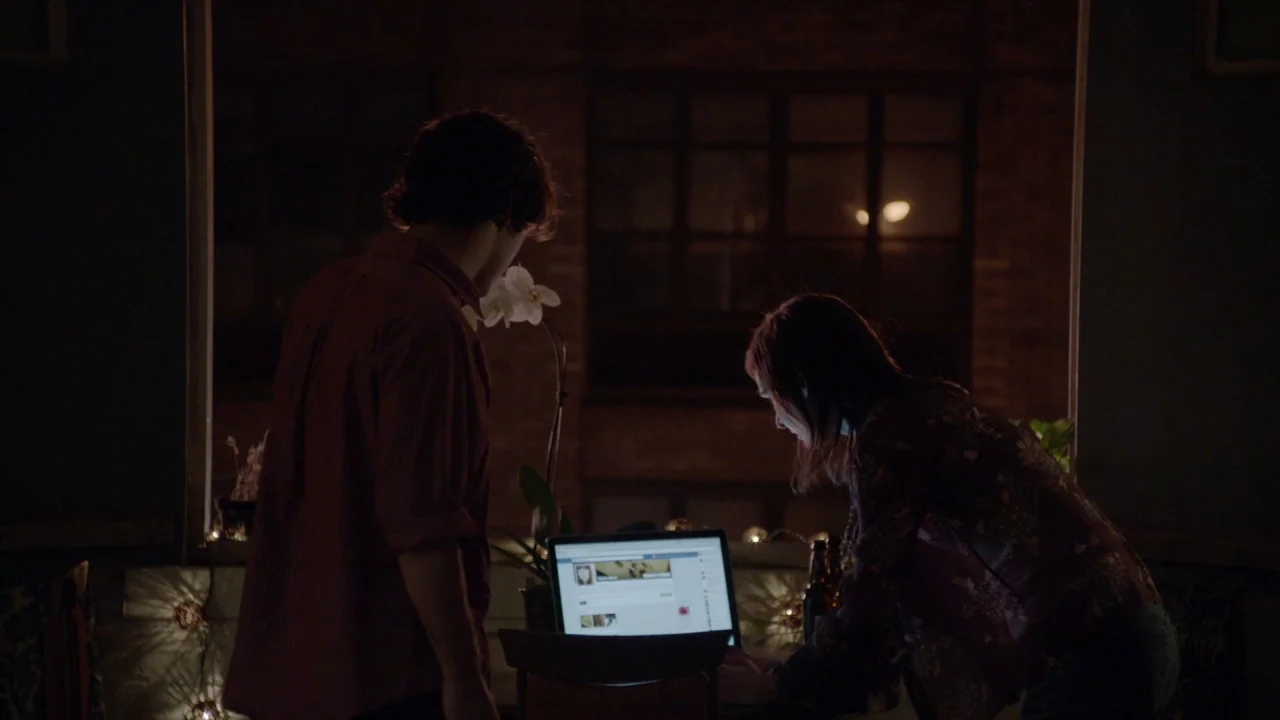 The Heart Machine (2014) movie still: medium — A dimly lit interior space at night features a laptop screen glowing on a table. A man and a woman…