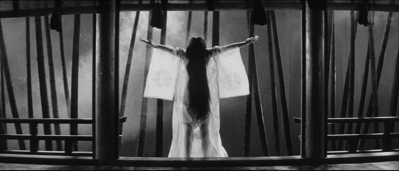 Kuroneko (1968) movie still: fullbody — A dark wooden Japanese temple veranda overlooks a dense and misty bamboo grove at night. A woman in a…