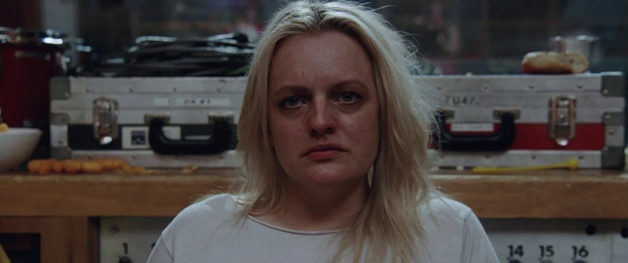 Her Smell (2018) movie still: closeup — A recording studio workspace features aluminum equipment cases stacked behind the subject. A woman faces the…
