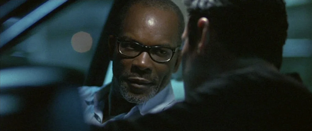 Boarding Gate (2007) movie still: medium — A man sits inside a vehicle at night with blue ambient light filtering through. He turns his head to face…