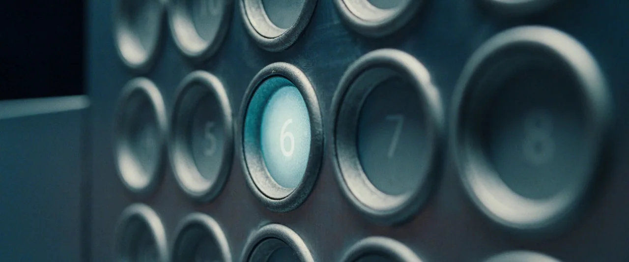 All Of Us Strangers (2023) movie still: closeup — A close-up view of a metal elevator control panel with numbered push buttons. The button labeled…