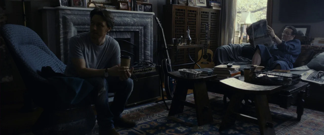 The Disappearance of Eleanor Rigby: Him (2014) movie still: wide — A cluttered living room contains a marble fireplace, acoustic guitar, and dark…