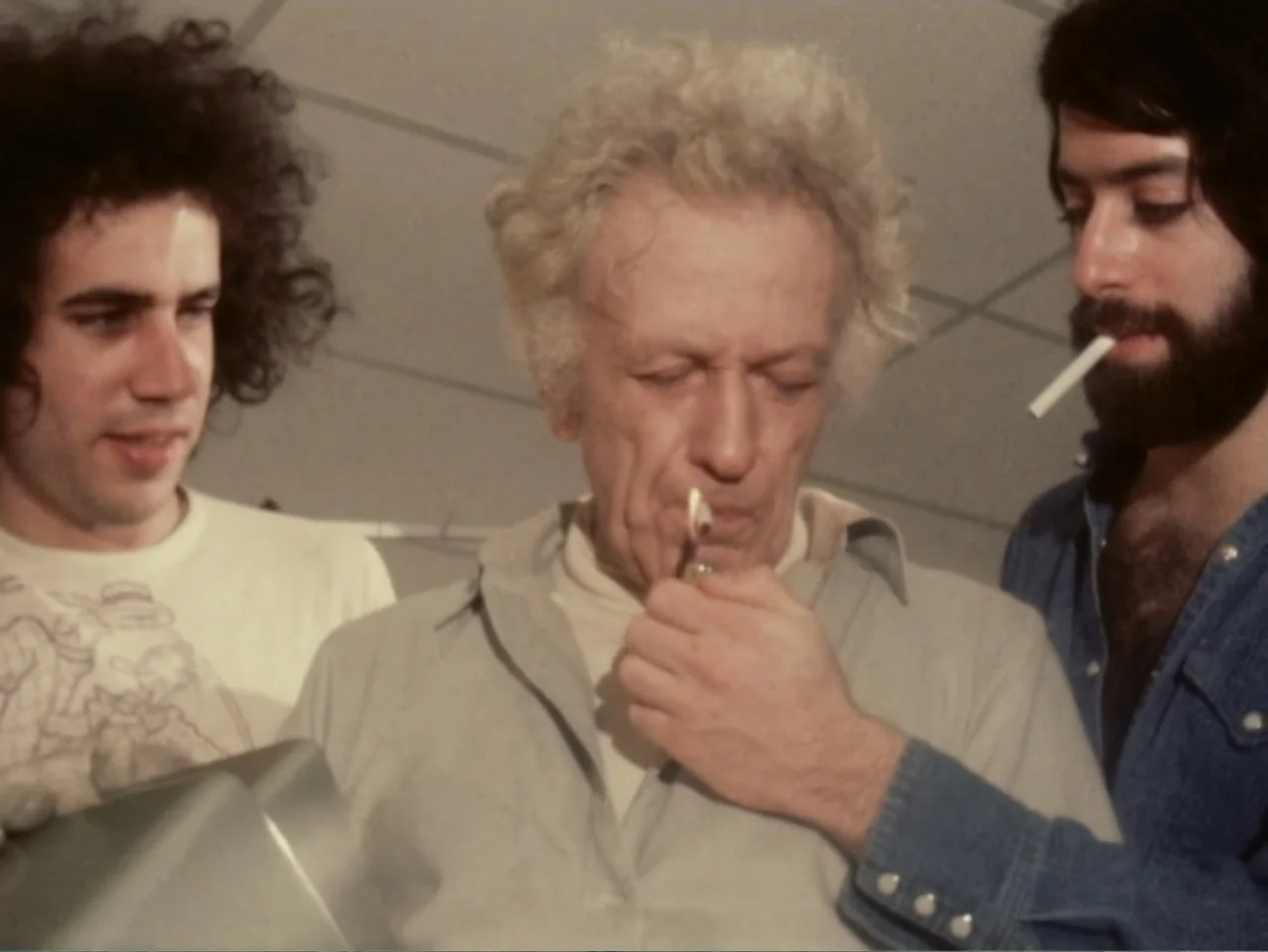 Don't Expect Too Much (2011) movie still: medium — A mundane office interior features a drop ceiling and three men standing together. One elderly…