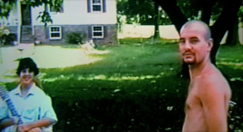 Gummo (1997) movie still: medium — A suburban residential property features a white two-story house with a green lawn. Two young men stand in the…