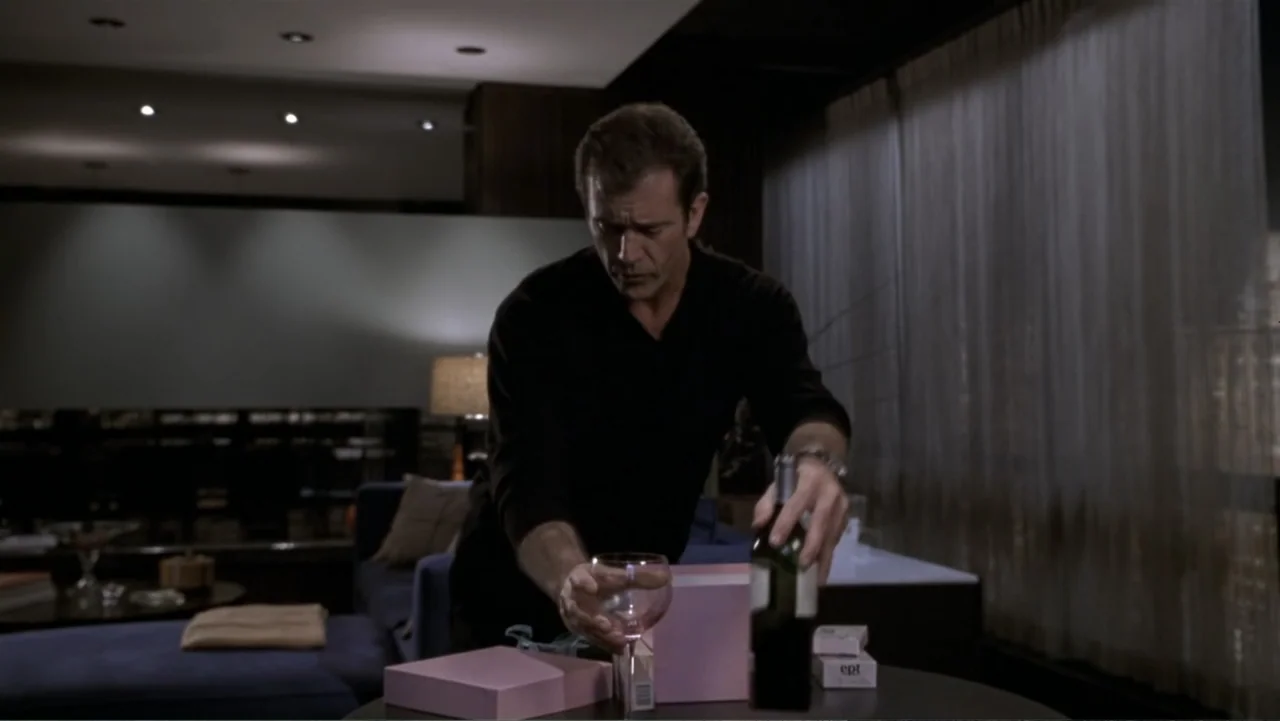 What Women Want (2000) movie still: medium — A dimly lit modern apartment interior with a dark blue sofa and sheer curtains. A middle-aged man in a…