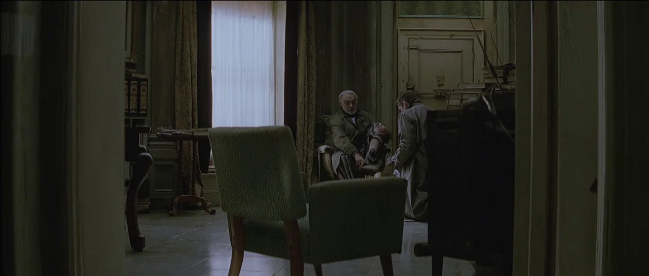 Finding Forrester (2000) movie still: wide — A dark study with stacks of books and an armchair near a window. Two men occupy the room with one…