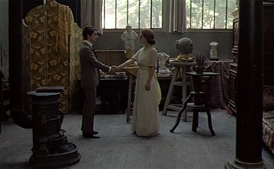 Two English Girls (1971) movie still: fullbody — An artist studio contains various sculptures, a wooden folding screen, and a cast iron stove. A man…