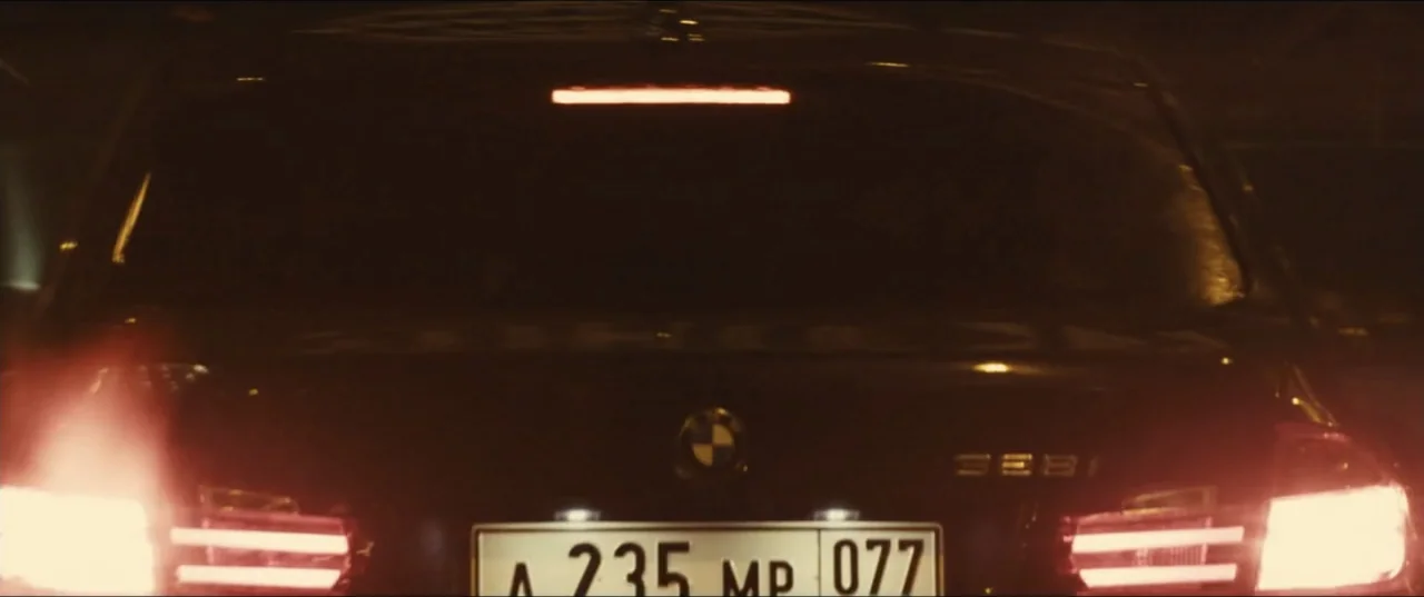 Jack Ryan: Shadow Recruit (2014) movie still: medium — A close view of the rear of a black BMW sedan at night. The taillights are glowing bright red…