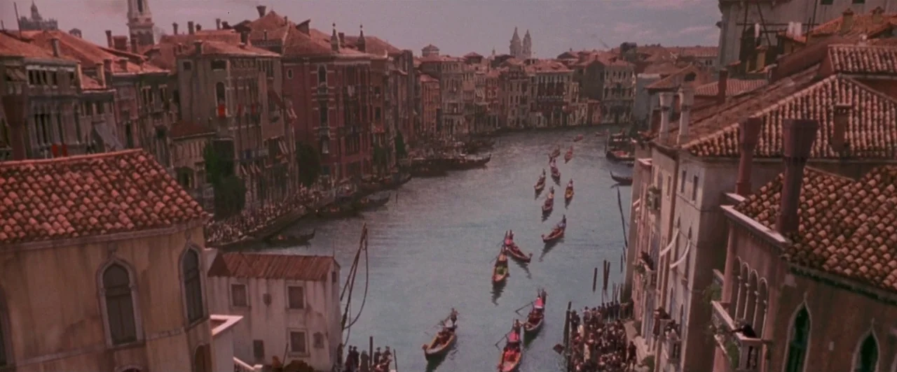 Dangerous Beauty (1998) movie still: establishing — An aerial view overlooks the Grand Canal lined with dense, aged brick buildings. Multiple long…