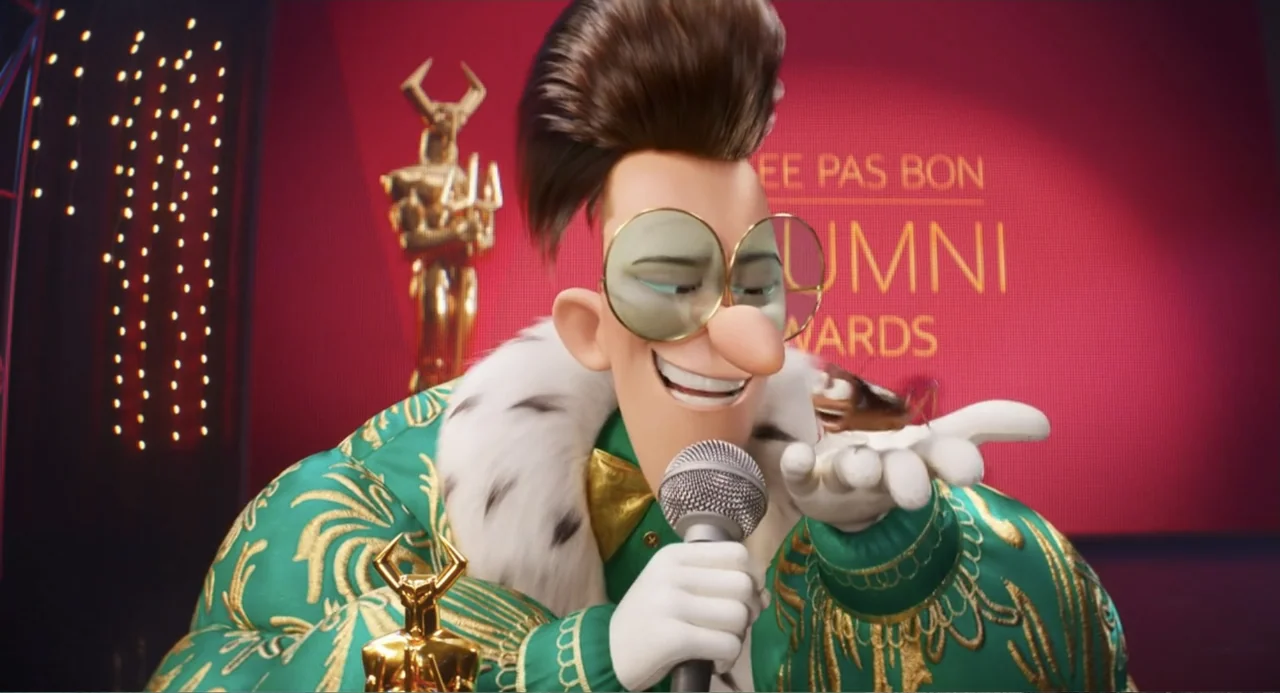Despicable Me 4 (2024) movie still: medium — A man with a large pompadour stands on a stage with a red backdrop. He holds a microphone in one hand…