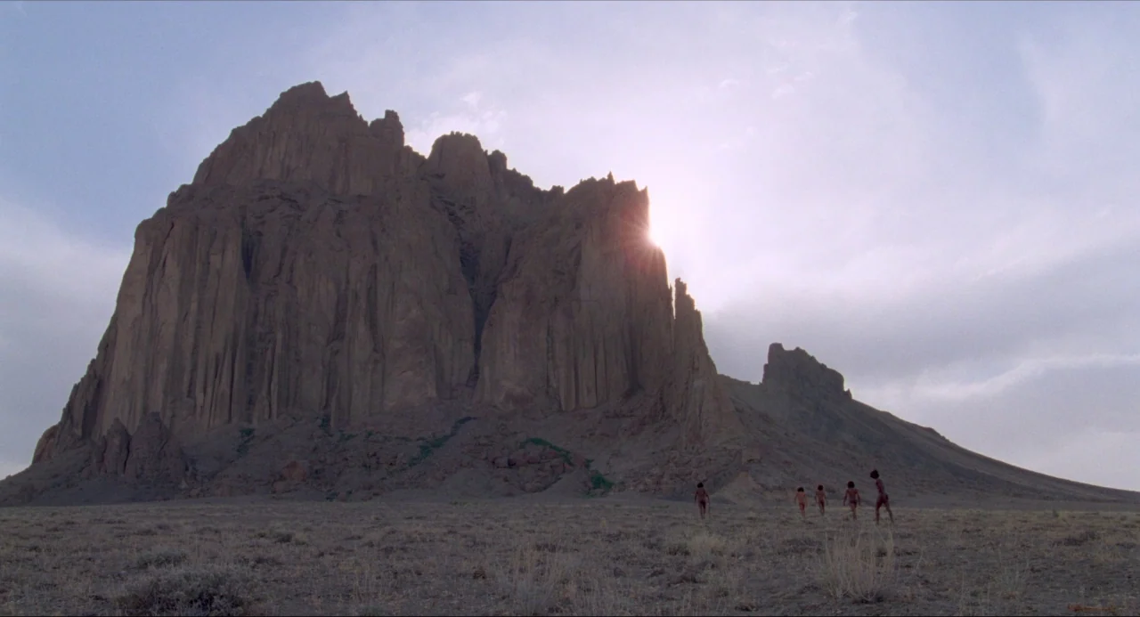 Voyage of Time (2016) movie still: wide — A vast, arid desert plain lies before a massive, craggy volcanic mountain formation. A small group of…