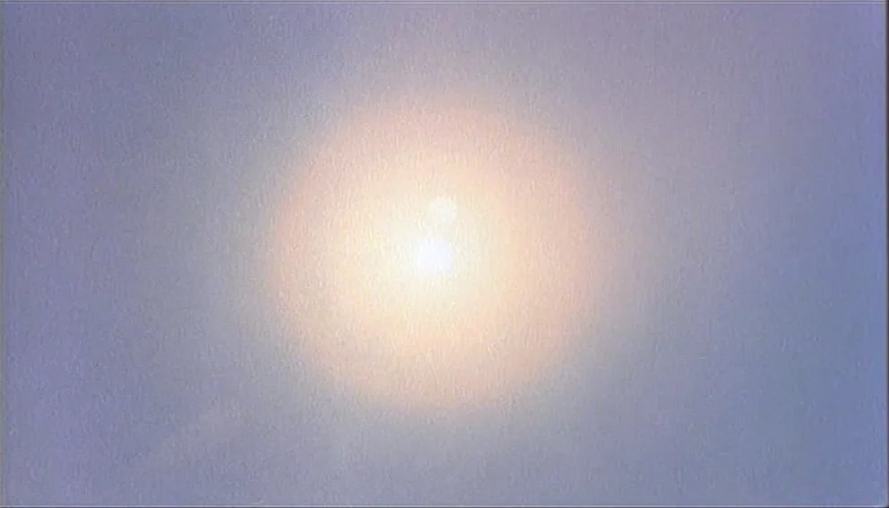 Labyrinth of Passion (1982) movie still: establishing — A bright sun sits in a clear blue sky. Light radiates from the center.