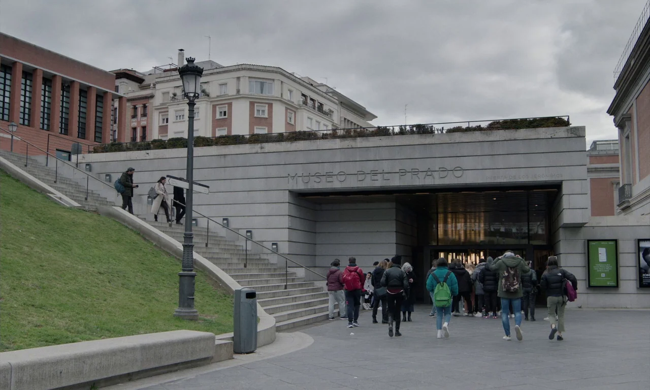 Close Your Eyes (2023) movie still: wide — A stone-walled entrance to the Museo del Prado is nestled into a gentle grassy slope. Numerous visitors…