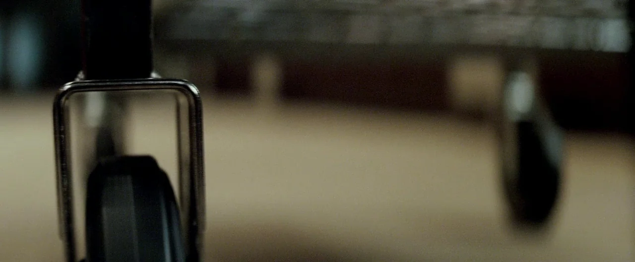 Michael Clayton (2007) movie still: closeup — The metal casters of a piece of medical equipment sit on a carpeted floor. The focus remains tightly…
