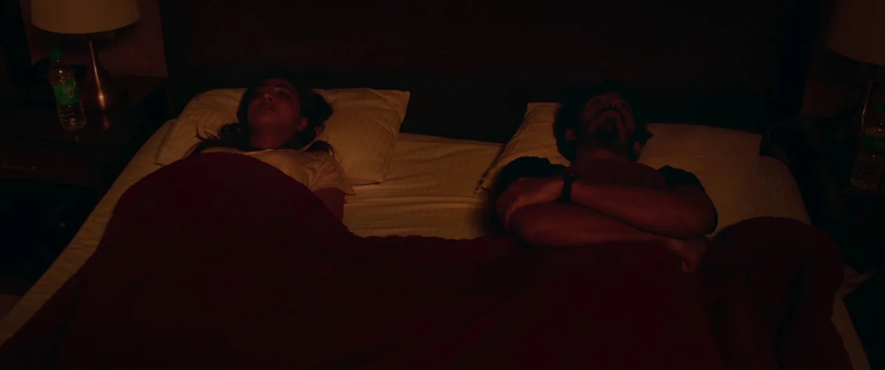 The Wedding Guest (2018) movie still: medium — A dark bedroom at night with a man and woman lying side by side. They are both looking up at the…