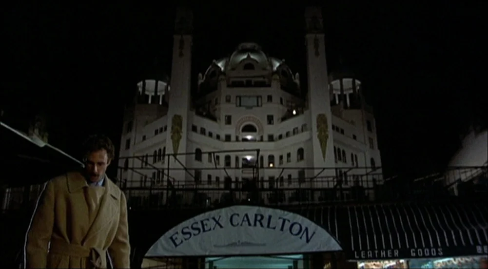 The King Of Marvin Gardens movie still: medium — A man stands before a brightly lit ornate building at night. A marquee sign indicates the…