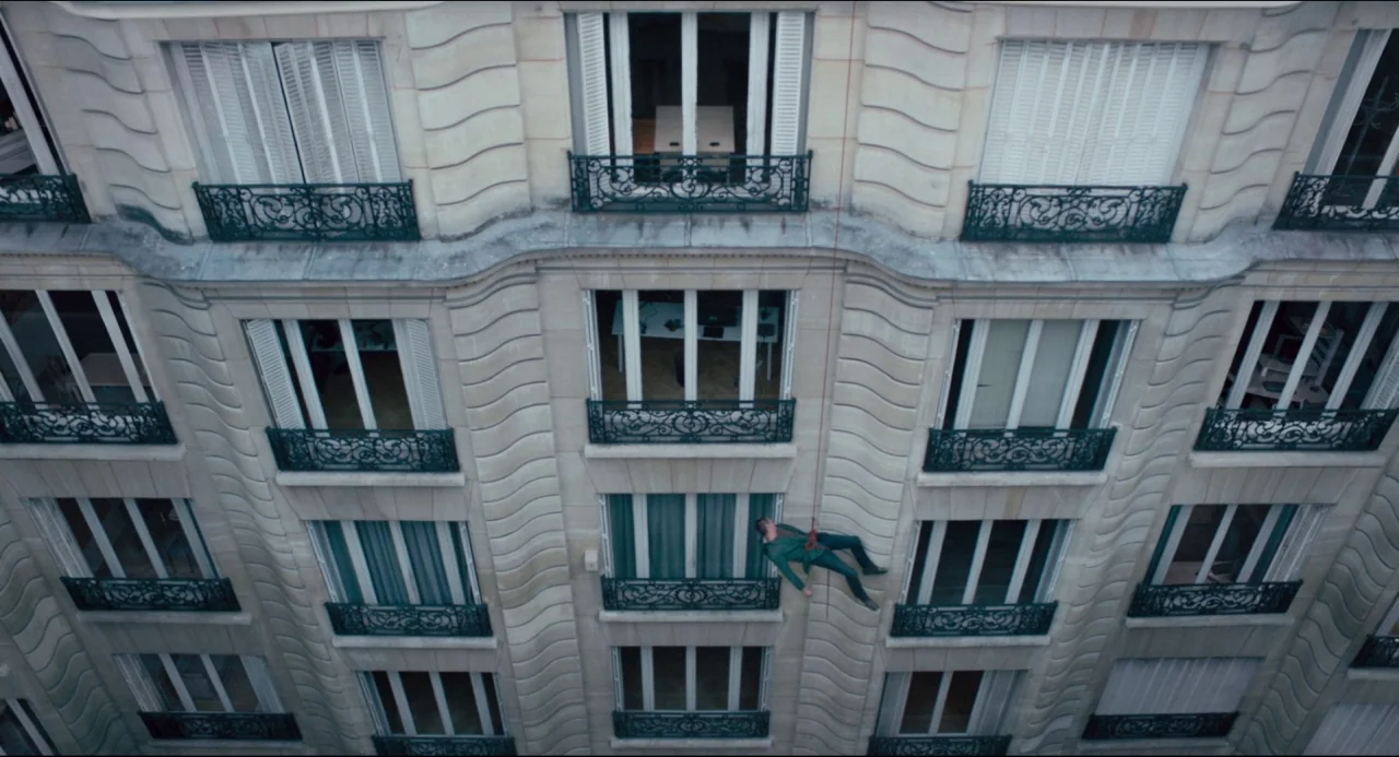 The Night Eats the World (2018) movie still: wide — A cream-colored limestone apartment building in Paris features multiple tiers of wrought-iron…