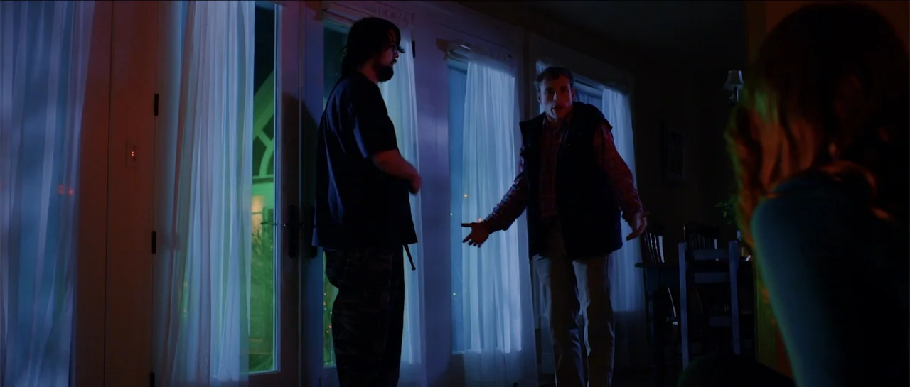 Halloween III: Season of the Witch (1982) movie still: medium — A dimly lit living room at night features sliding glass doors covered by white…