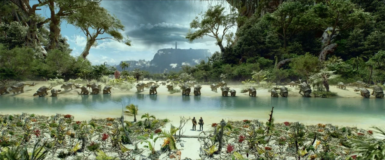 Monster Hunter (2020) movie still: wide — A lush prehistoric-style valley features a wide river bordered by dense tropical foliage. Two human…