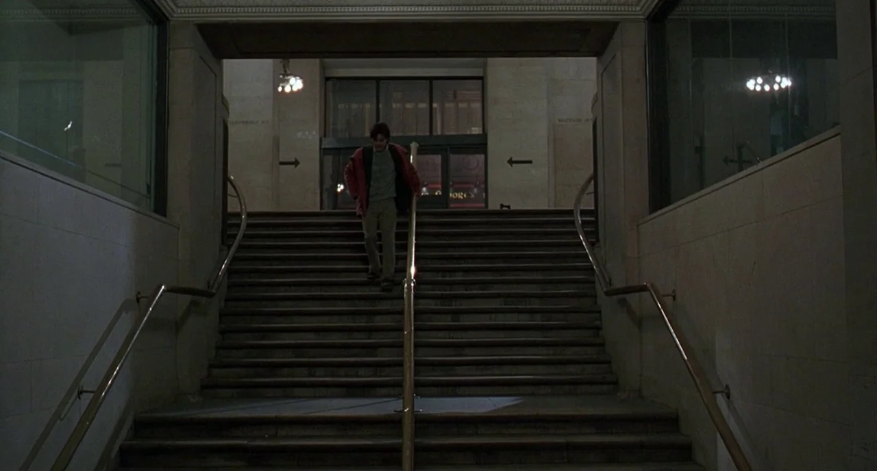 The Ice Storm (1997) movie still: wide — A stone staircase leads down into an urban transit or building access area. A man wearing a red jacket…