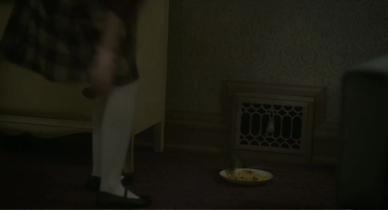 Orphan: First Kill (2022) movie still: medium — A dimly lit room features patterned wallpaper and a metal floor register. A young child in white…