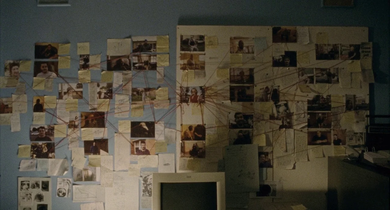 Snowtown (2011) movie still: wide — A blue wall is covered with a complex web of photographs and paper notes. Red strings connect various items…