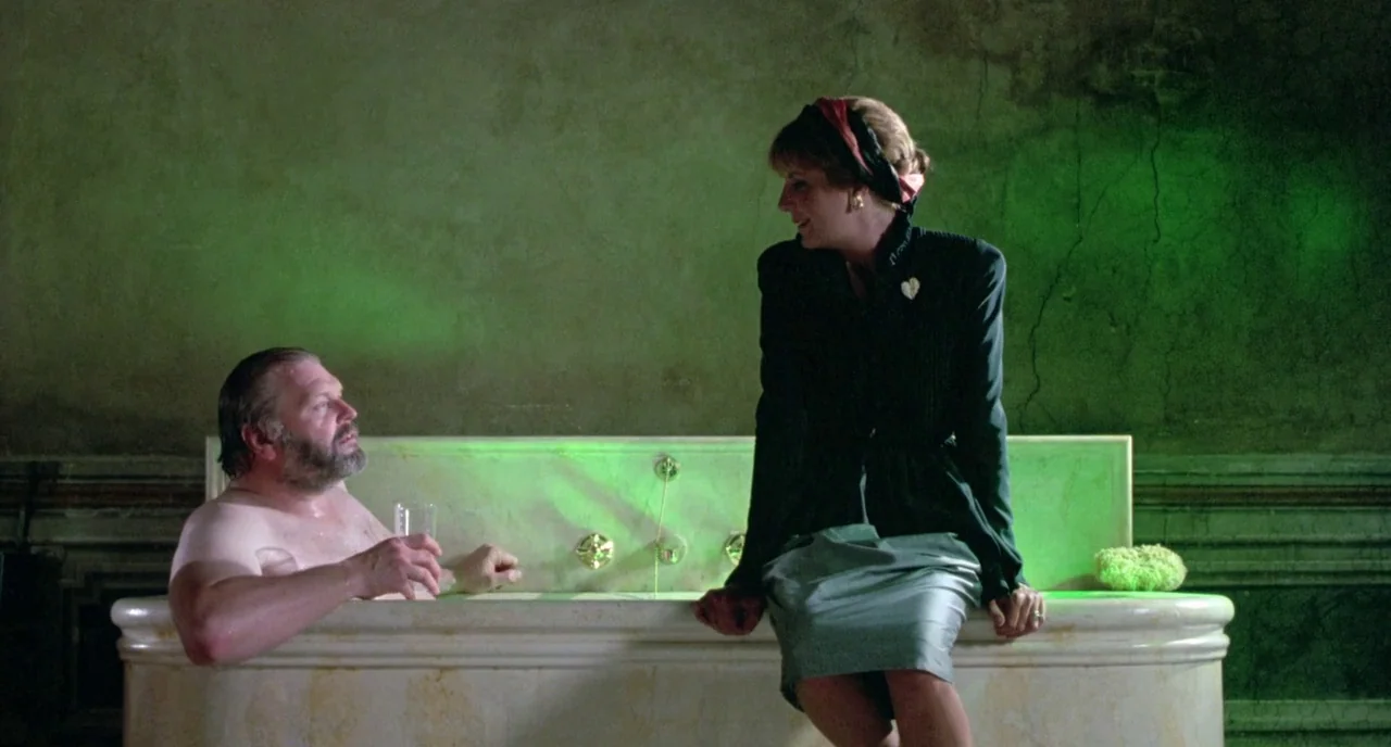 The Belly of an Architect (1987) movie still: medium — An opulent, vintage-tiled bathroom with aged walls features a large stone bathtub. A man…