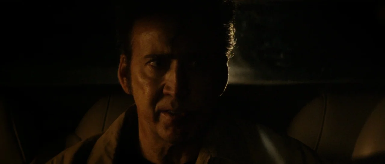 Dog Eat Dog (2016) movie still: closeup — A man sits inside the dimly lit cabin of a vehicle at night. He stares forward while rim light defines his…