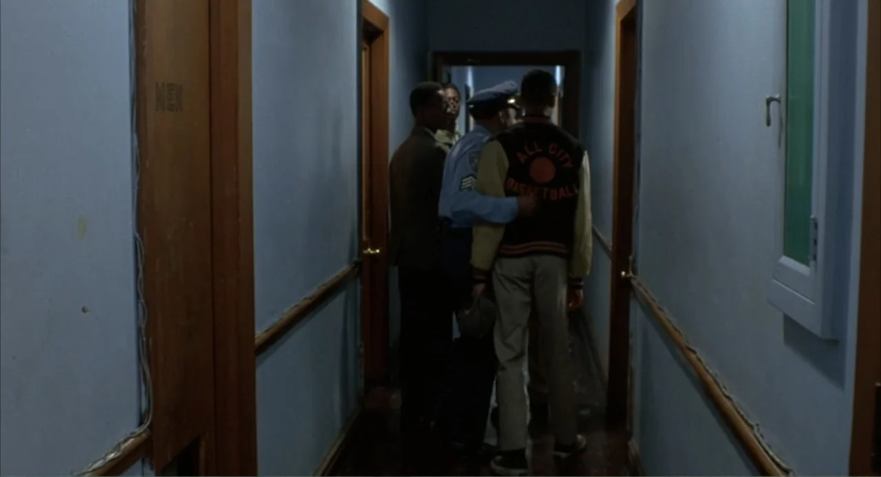 Cooley High (1975) movie still: fullbody — A narrow residential hallway with pale blue walls and brown door frames. Three men stand together in the…