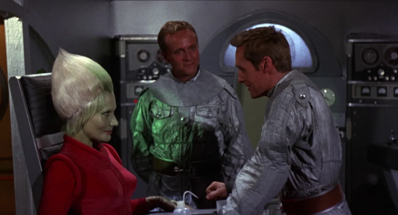 Queen of Blood (1966) movie still: medium — A 1960s science fiction spacecraft bridge features metallic walls with control panels and dials. Two men…