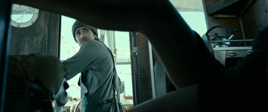 Ondine (2009) movie still: medium — A cramped and dark nautical vessel cabin with wood paneling and simple furniture. A man in work clothes turns…