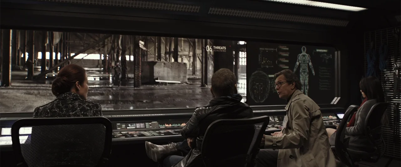 RoboCop (1987) movie still: medium — A high-tech control room contains several people seated before large wall-mounted data monitors. The group…
