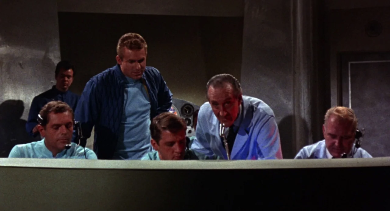Queen of Blood (1966) movie still: medium — A 1960s mission control room features men working at a curved console with headsets. Five men operate…