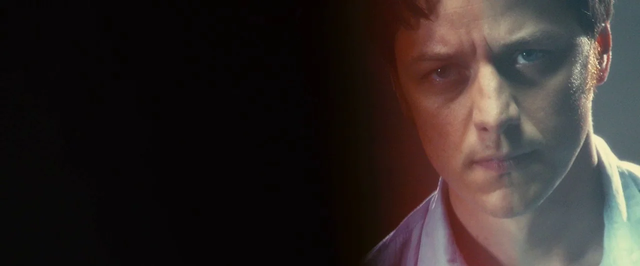 Trance (2013) movie still: closeup — A man's face occupies the right side of the frame against a black void. He faces the camera directly while his…