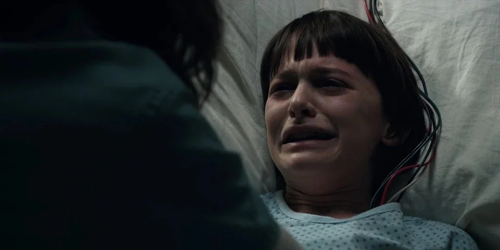 Stranger Things (2016) movie still: closeup — A hospital bed with a white pillow and multiple colored electrical wires attached. A young boy in a…