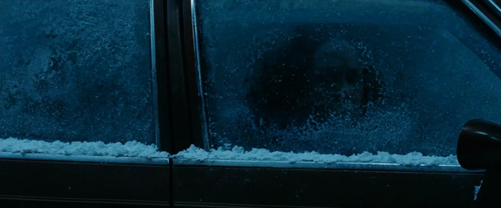 Wind Chill (2007) movie still: medium — A snow-covered car window shows frost patterns on the glass surface. A person's face is visible behind the…