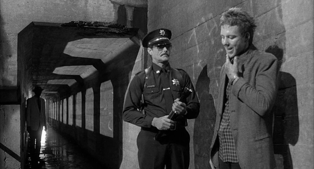 Rumble Fish (1983) movie still: medium — A concrete underpass features repeating geometric pillars and open rectangular windows along one side. A…