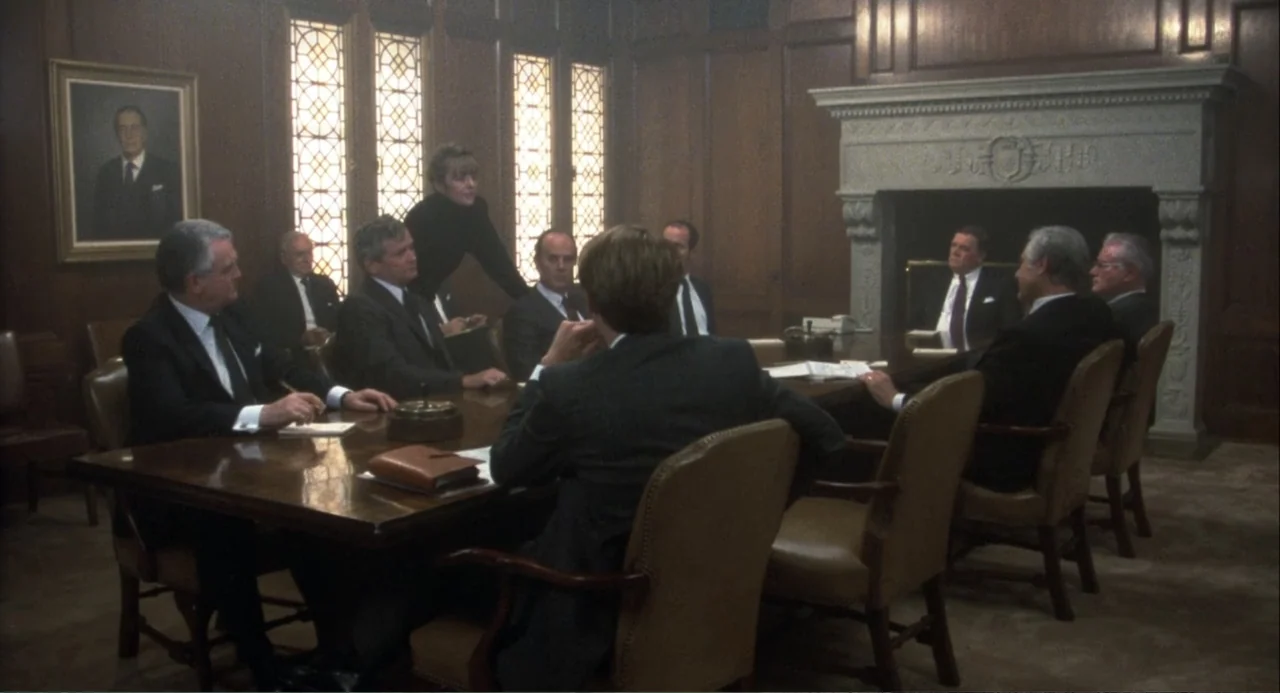 Baby Boom (1987) movie still: medium — A wood-paneled boardroom features an ornate stone fireplace and high-backed leather chairs. Several…