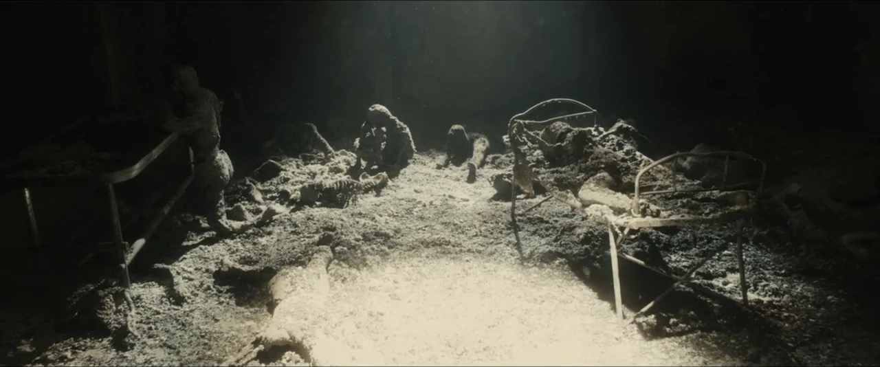 World War Z (2013) movie still: wide — A desolate expanse covered in thick volcanic ash containing human remains and metal frames. Multiple figures…
