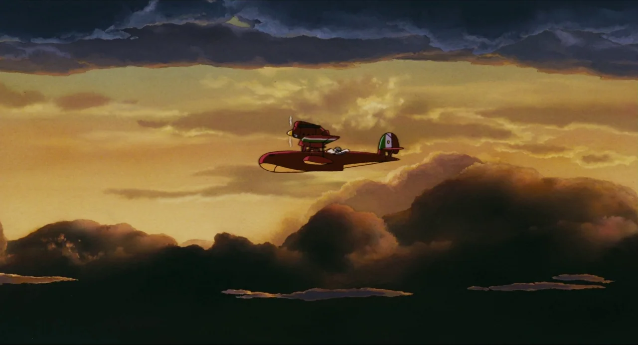 Porco Rosso (1992) movie still: wide — A red seaplane cruises through a vast expanse of clouds during a golden sunset. Dark storm clouds frame the…