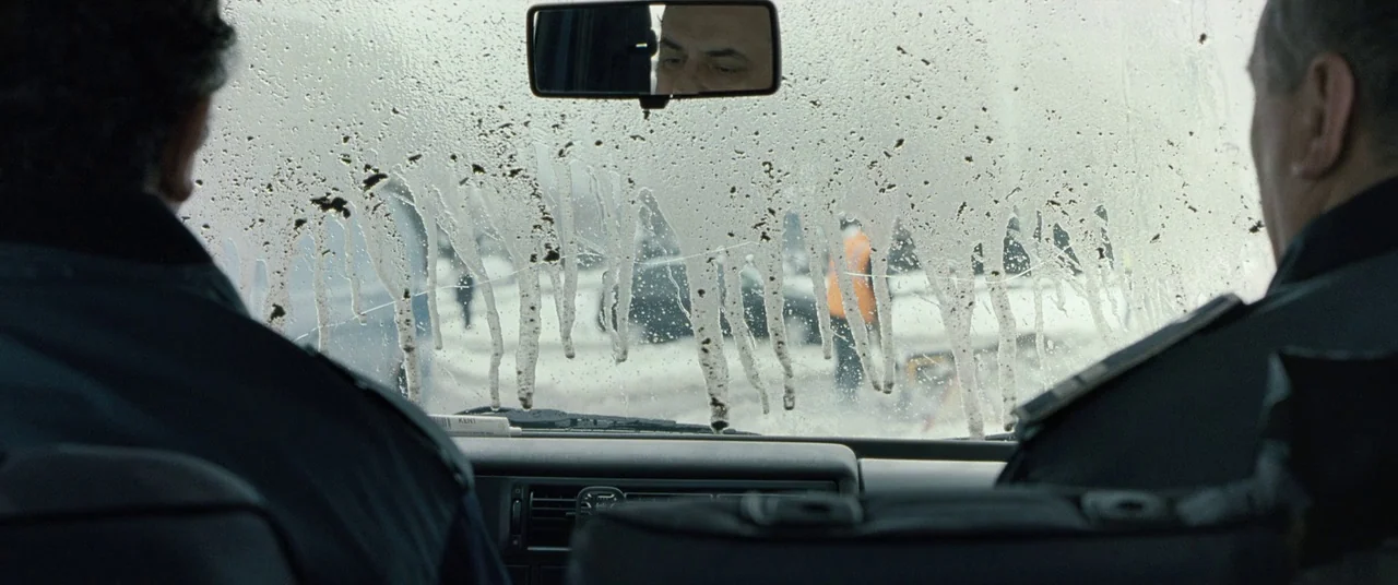 Beyond the Hills (2012) movie still: medium — The interior of a vehicle viewed over the shoulders of two police officers. Streaks of dirt and water…